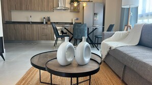 A modern kitchen with wooden cabinets, a dining area with a table and chairs, and a living room with a sofa and a coffee table. - The Windown Suite Near Downtown Punta Cana (Higuey)