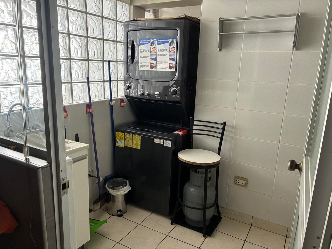 Una cocina compacta con estufa a gas, un lavamanos pequeño y un ventanal con vidrio esmerilado.