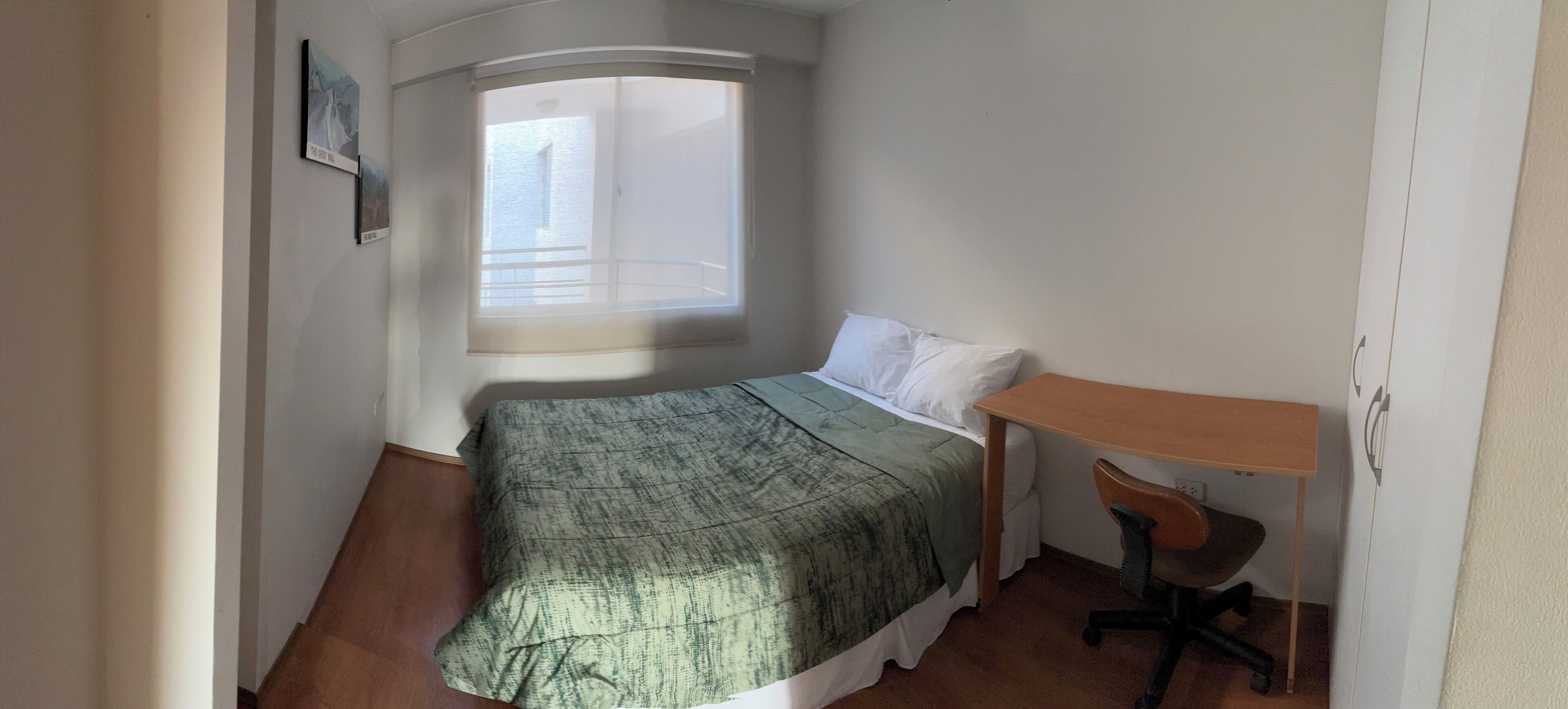 Un dormitorio pequeño con cama, escritorio y ventana.