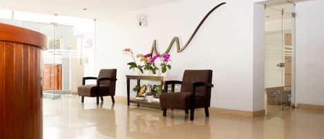 A modern lobby with two brown chairs, a wooden reception desk, and a wall-mounted decorative piece.