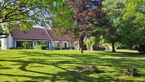A house with a red-tiled roof, surrounded by well-maintained lawns and trees. - 10 mn from Wimereux beach, charming renovated farmhouse in a green setting (Wierre-Effroy)