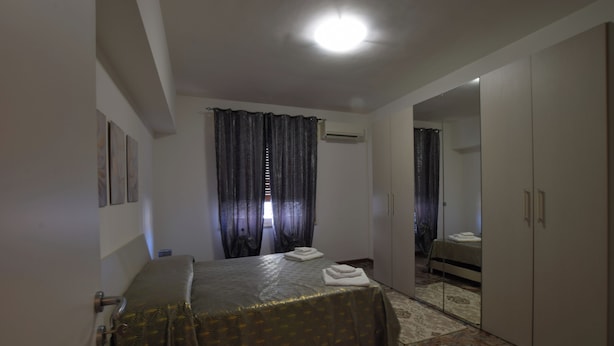A bedroom with a bed, a wardrobe, a mirror, and a window with curtains. - B&b on the course, Reggio Calabria (Reggio Calabria)