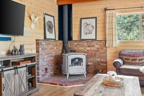 A cozy living room with a brick fireplace, a television mounted on the wall, and a comfortable sofa.
