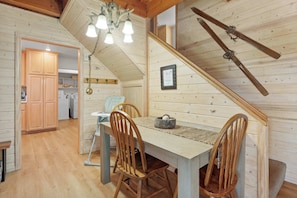 A wooden interior with a dining table, chairs, a staircase, and a kitchen area.