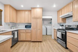 A modern kitchen with wooden cabinets, stainless steel appliances, and a marble backsplash.