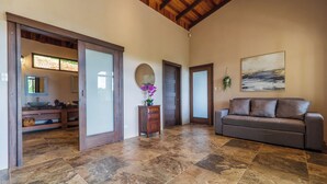 A spacious living area with a large gray sofa, a wooden ceiling, and a tiled floor. - Getaway Charming 2-bedroom house secluded with Ocean Breeze (San José Province)