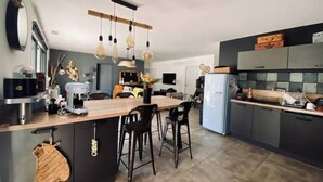 Une cuisine moderne dotée d’un îlot central, de luminaires suspendus et d’un réfrigérateur.