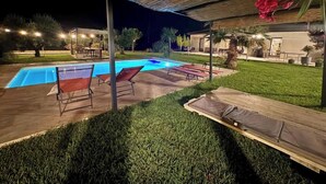 Un jardin avec une piscine, des chaises longues et un espace patio.