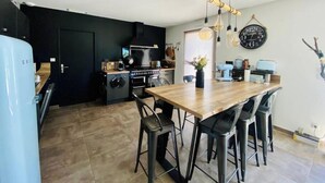 Une cuisine moderne avec un poêle noir, une table à manger en bois et des tabourets de bar noirs.