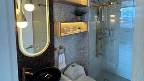 Ein modernes Badezimmer mit einem großen Spiegel, eingebauten Regalen, einem schwarzen Waschbecken, einer Toilette und einer Duschkabine.