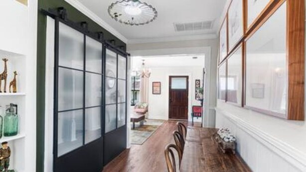 A dining area with a long wooden table, chairs, and a black sliding door with frosted glass panels. - Downtown Mobile: Pet Friendly + 5m Walk (Mobile)