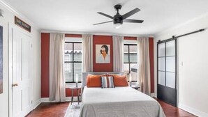 A bedroom with a bed, a ceiling fan, a window with curtains, and a sliding door. - Downtown Mobile: Pet Friendly + 5m Walk (Mobile)