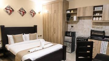 A hotel room with a bed, a kitchenette, and a dining area.