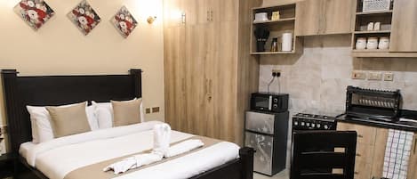 A hotel room with a bed, a kitchenette, and a dining area.