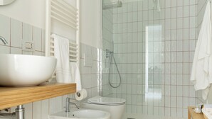 Un baño moderno con un lavamanos grande blanco, un inodoro, un bidé y una zona de ducha.