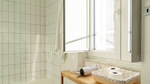 Un baño moderno con ducha, tocador de madera y un amplio ventanal que proporciona luz natural.