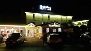 A hotel named "HAVANA HOTEL" with a well-lit entrance, multiple parking spaces, and a visible restaurant area. - Havana (Malay-le-Grand)