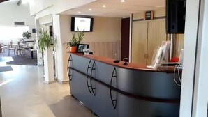 A reception area with a counter, a television mounted on the wall, and a potted plant. - Havana (Malay-le-Grand)
