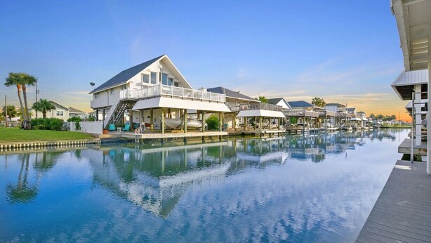 A waterfront property with a swimming pool, a covered deck, and a boat dock. - Upscale Waterfront Boat Lift~Kayaks~Pets~Sleeps12 (Galveston)