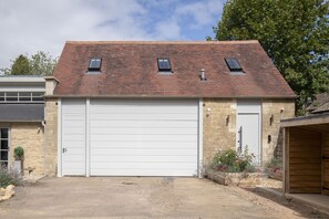 A two-story building with a large garage door, a stone facade, and a sloped roof with skylights.