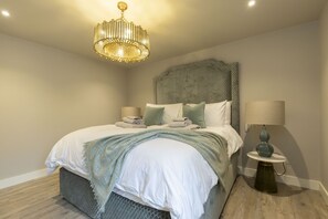 A neatly made bed with a headboard, a bedside lamp, and a decorative light fixture.