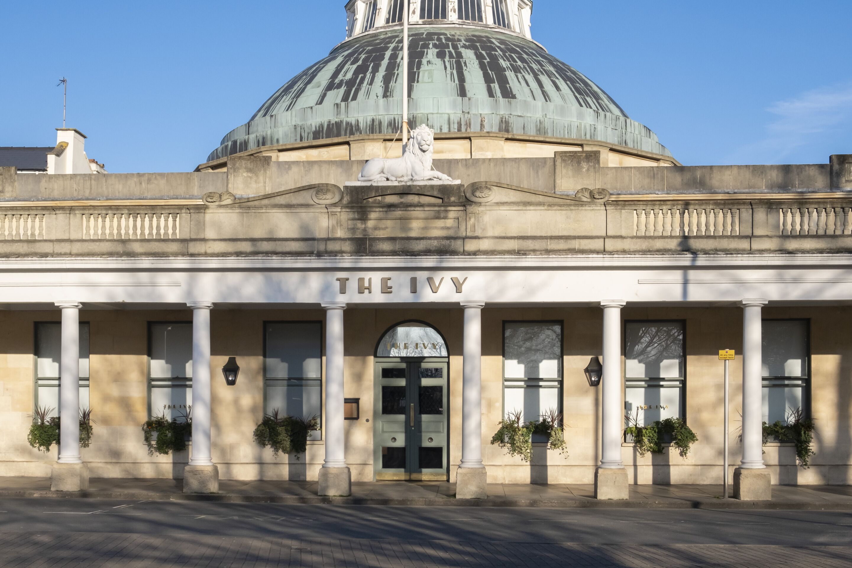 A building with a large dome and a lion statue on the facade, named "THE IVY".