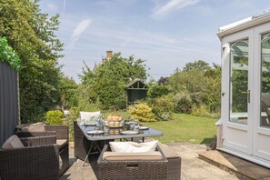 A patio area with wicker furniture, a table set for a meal, and a conservatory.