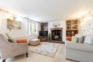 A living room with a fireplace, two sofas, a television, and a painting on the wall. - A Quaint, Relaxing 3-Bed Cottage in Eastington (Gloucestershire)