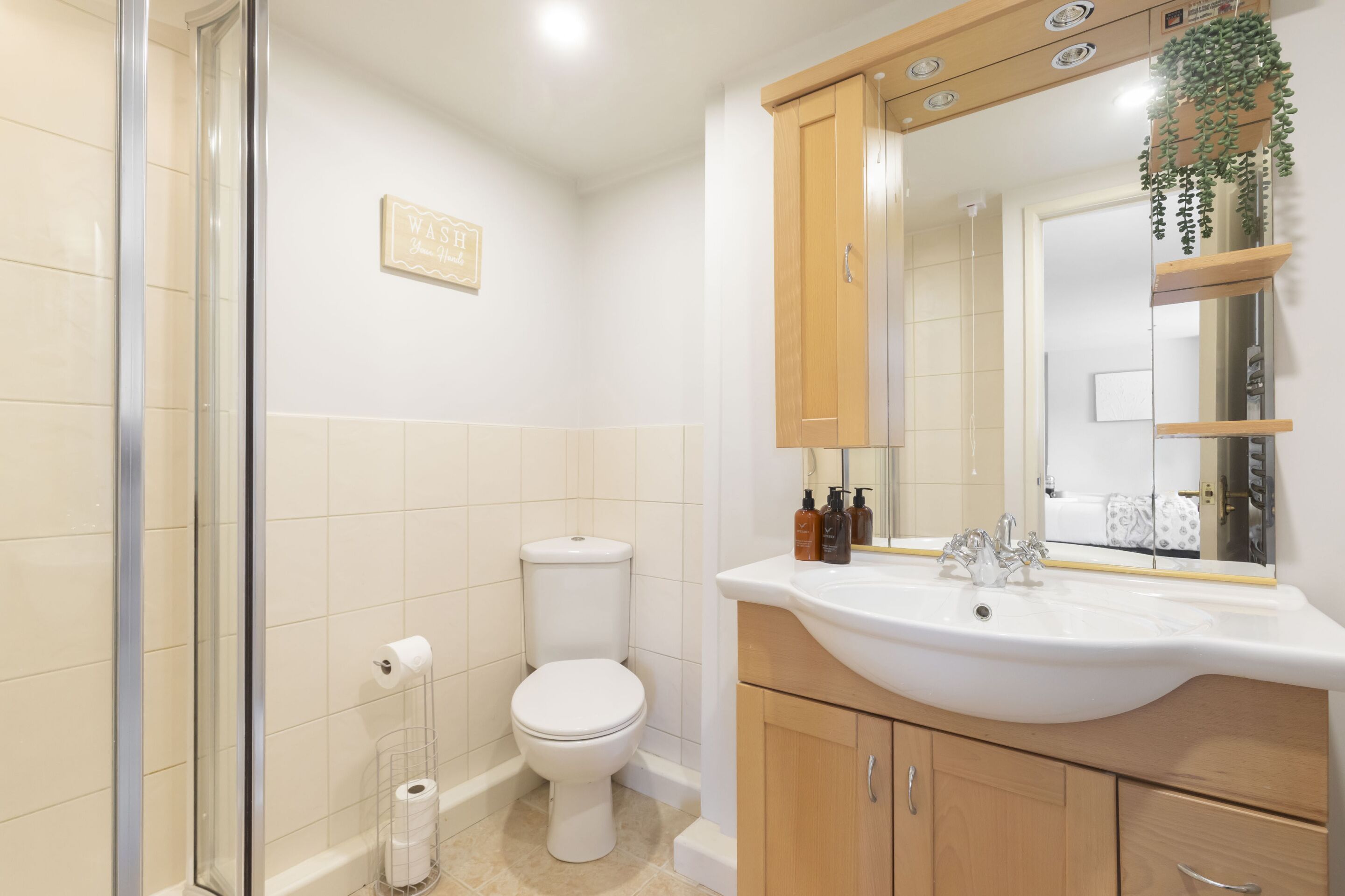 A bathroom with a toilet, sink, mirror, and shower area.