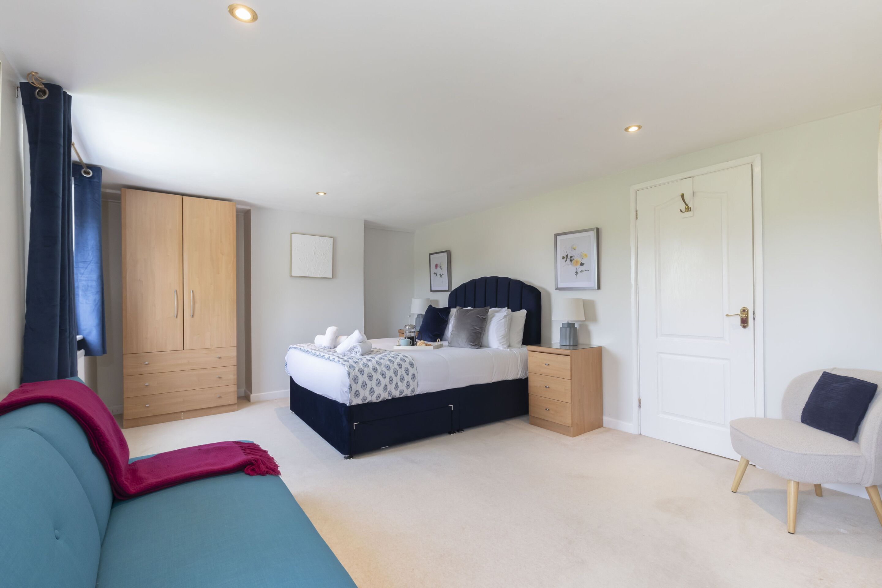 A bedroom with a bed, a wardrobe, a bedside table, a chair, and a door.