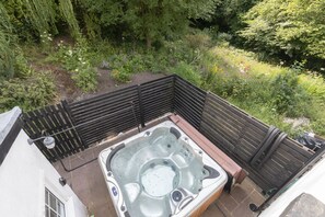 Ein Whirlpool in einem Garten mit einer Holzterrasse und einem Zaun.
