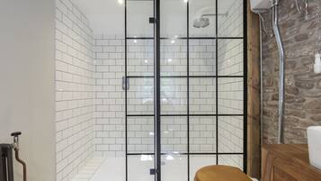 Ein modernes Badezimmer mit einer in Glas abgeschlossenen Dusche, weißen Fliesen und einem Holzkosmetikschrank.