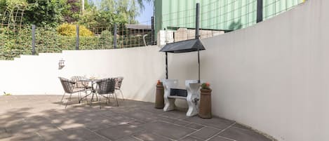 Een patio met een tafel en stoelen, een bank en een pergola.