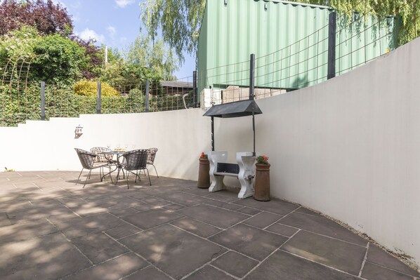 Un espace extérieur aménagé avec une table et des chaises, un banc et une structure en forme de pergola.