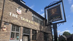 Skirrid Inn, en byggnad i sten med en traditionell pubskylt och en affisch som annonserar att det är Wales äldsta värdshus.