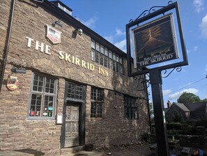 Le Skirrid Inn est un bâtiment en pierre doté d’une enseigne de pub traditionnelle et d’une affiche faisant la publicité du plus ancien pub du pays de Galles.