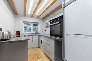 A modern kitchen with a built-in oven, a washing machine, and a refrigerator.