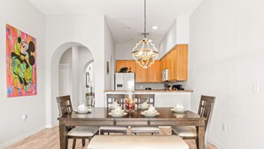 A dining area with a wooden table, chairs, and a bench. There is a chandelier above the table. - Caribe Cove Charm - For 8! (Kissimmee)