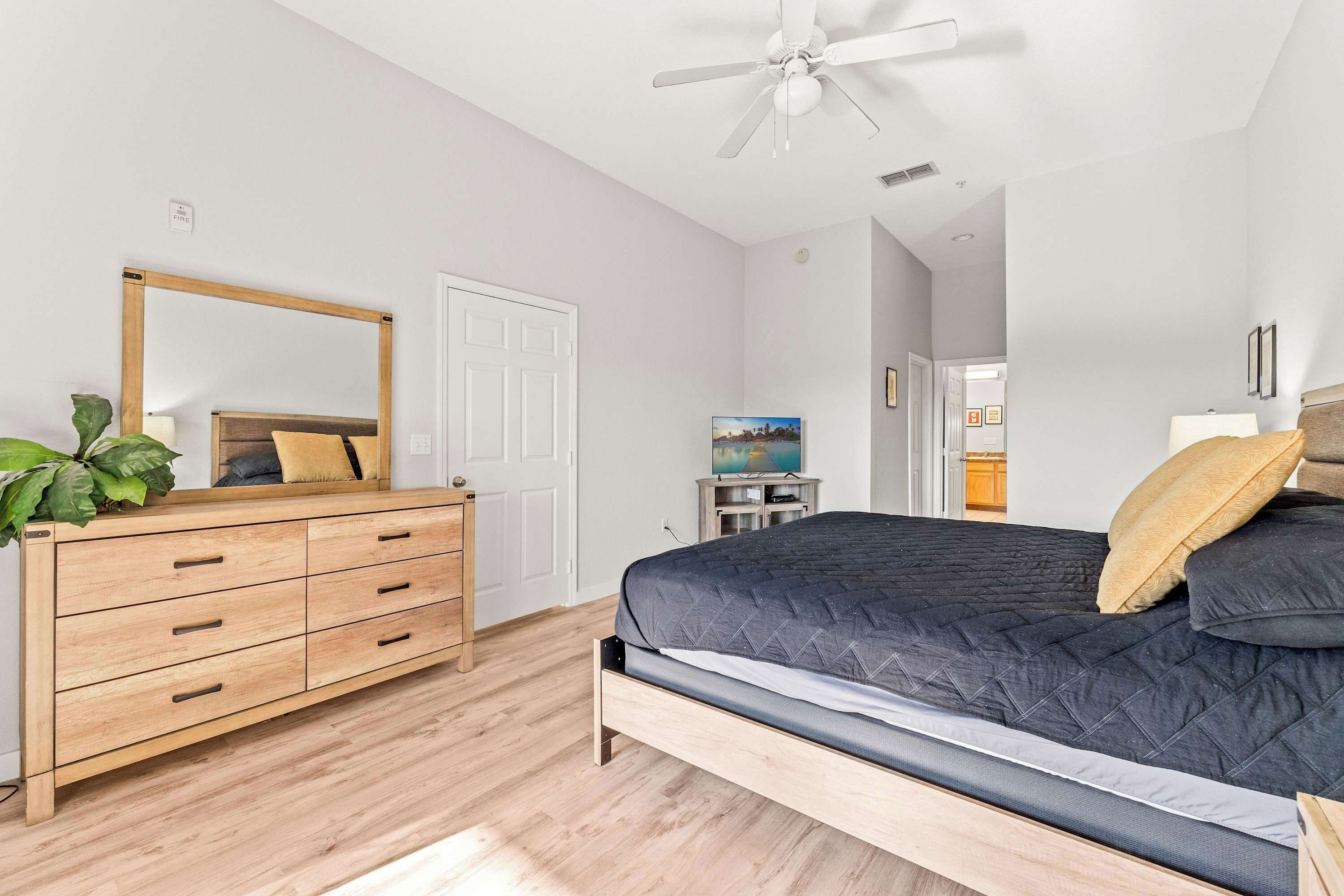 Un dormitorio con cama, cómoda y ventilador de techo.