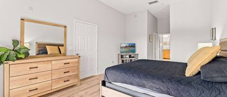 Un dormitorio con cama, cómoda y ventilador de techo.
