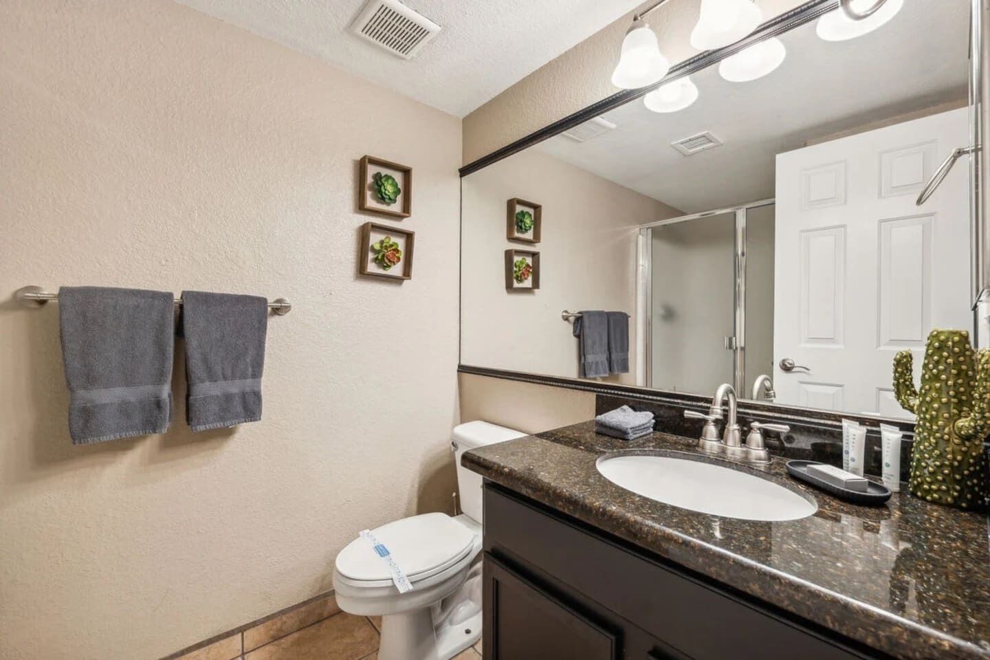 A bathroom with a toilet, sink, and mirror. There are two towels hanging on a towel rack.