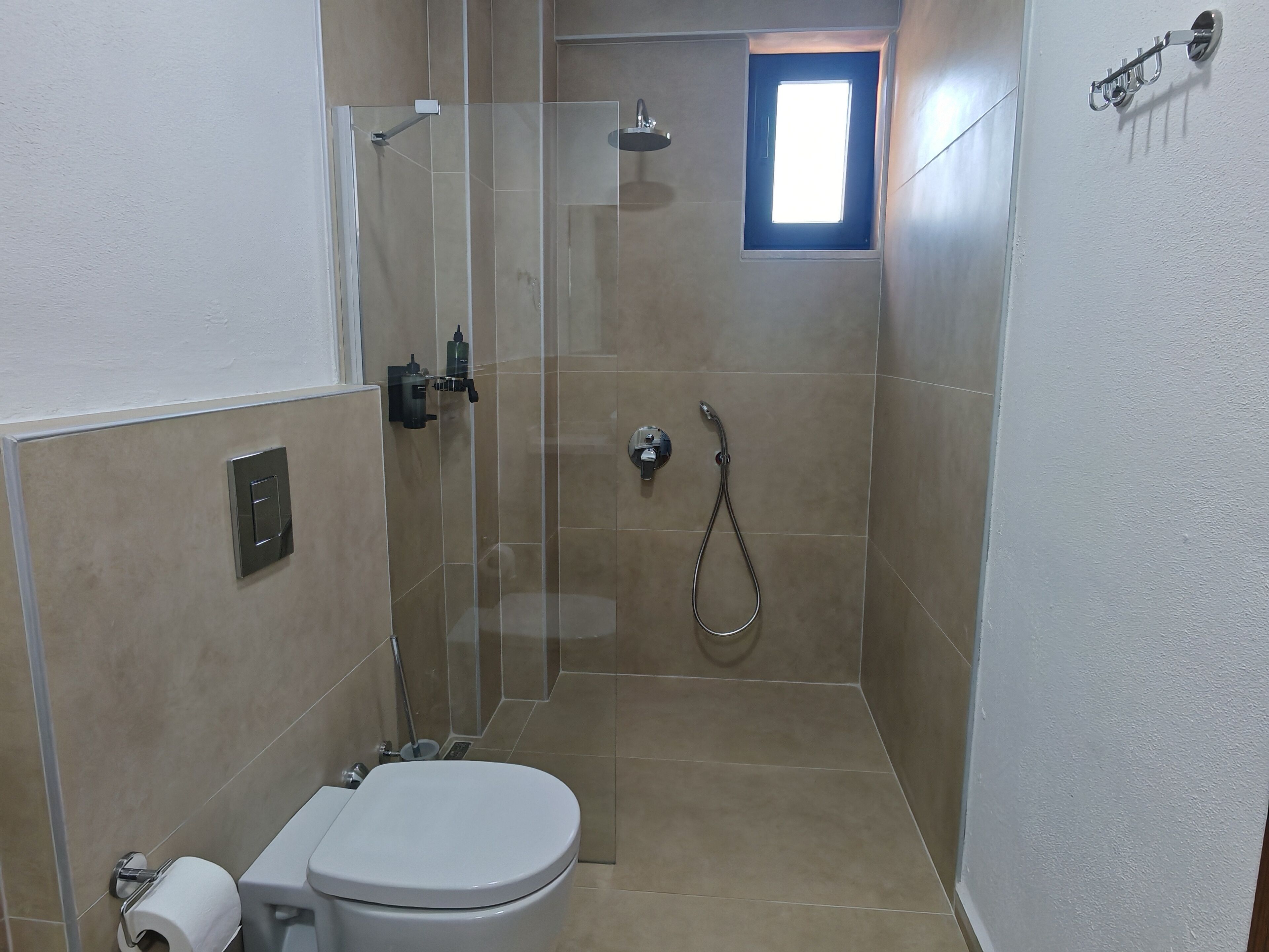 Un baño pequeño y cerrado con inodoro, ducha y ventana.