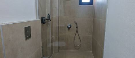 Un baño pequeño y cerrado con inodoro, ducha y ventana.