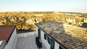 A building with a tiled roof and a balcony with chairs. - Sassi di Matera loft with terrace - free parking (Matera)