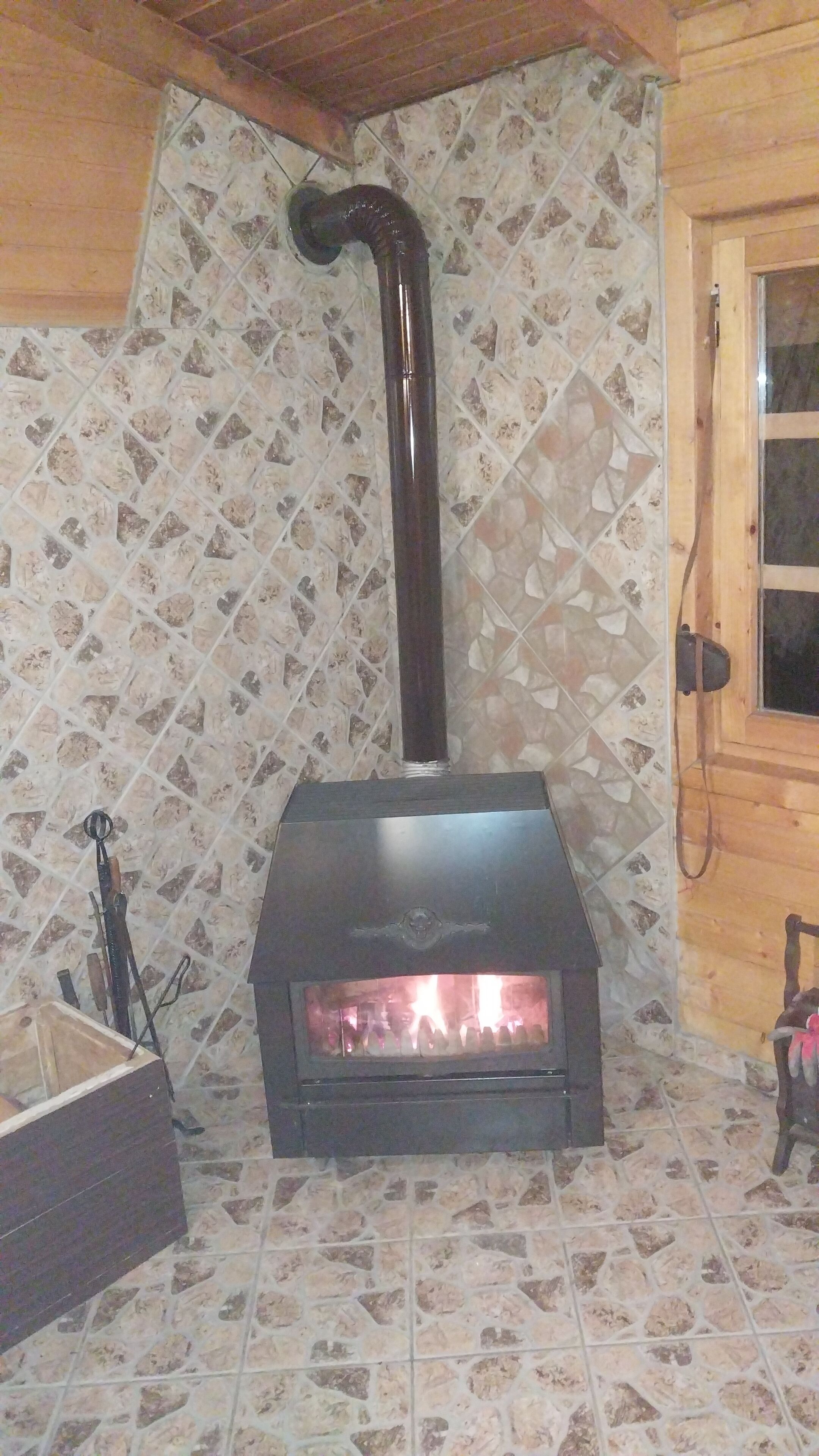 Ein Kaminofen mit Schornstein, eine Holztür und ein Fliesenboden.