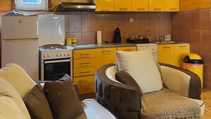 Ein gemütliches Blockhaus-Interieur mit Küchenzeile, Holzwänden, einer Couch und einem Essbereich.