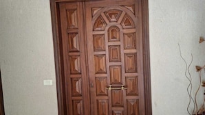 A wooden double door with a geometric pattern, a doorknob, and a small step leading to the entrance. - Belle Maison Bdadoun by Hansa  (Blaybel)