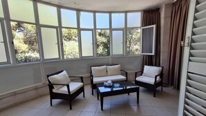 A room with a curved wall of large windows, a sofa set, and a coffee table. - Belle Maison Bdadoun by Hansa  (Blaybel)
