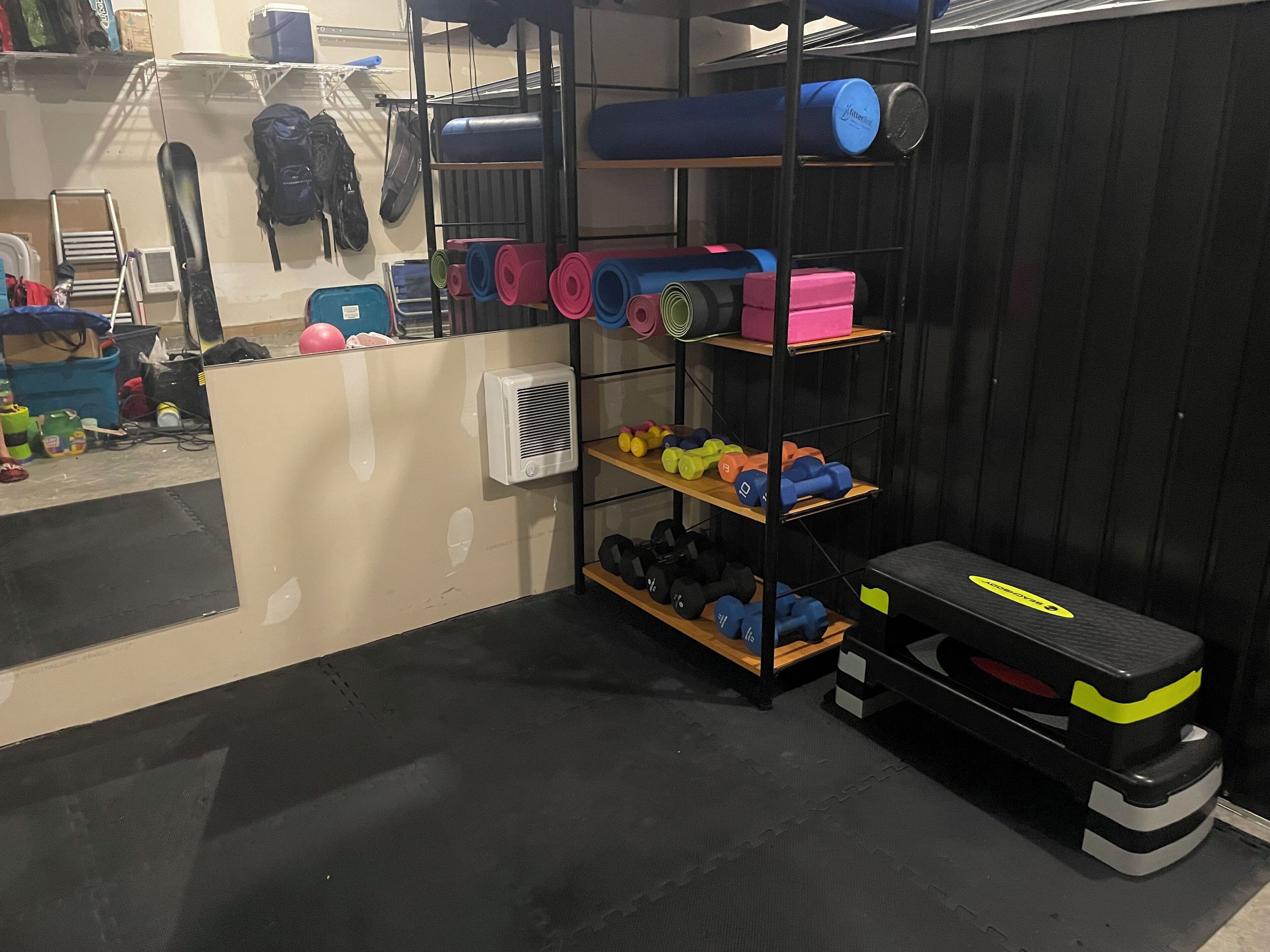 Un gimnasio con equipo de ejercicio, incluyendo mancuernas, colchonetas de yoga y una cinta de correr.