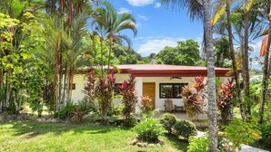 A house with a red roof, surrounded by lush greenery and palm trees. - Luxury Beachfront Retreat – 13BR Private Resort with Pool in Jacó (Jaco)